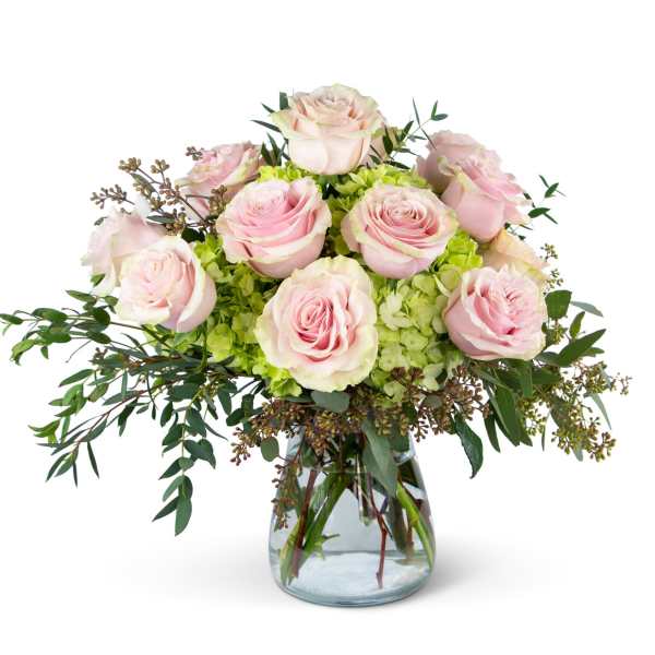 Pink roses arranged in a clear glass vase with green filler