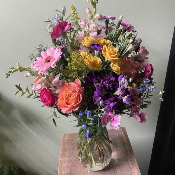 Mixed bouquet of pink, purple, yellow, and orange flowers in a glass vase