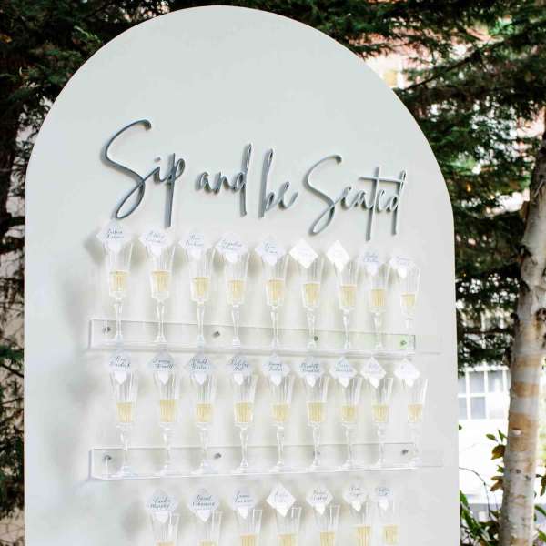 White seating chart board with rows of champagne flutes