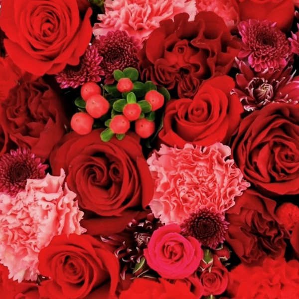 Dense red bouquet with roses, carnations, and small berry accents