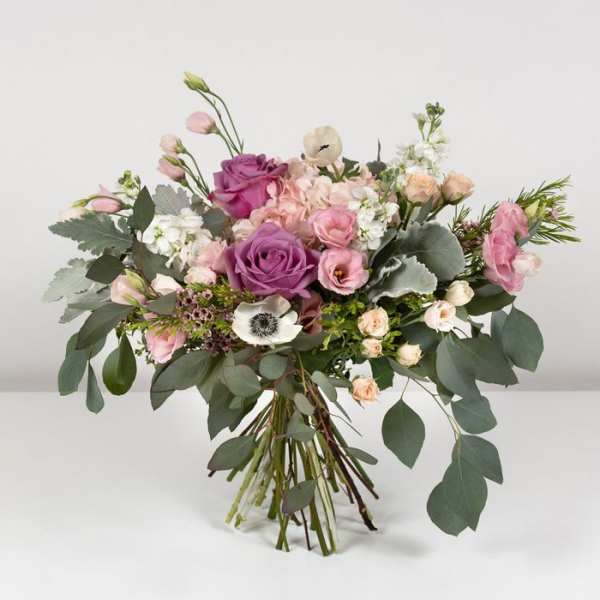Bouquet of pink and purple roses with white blooms and greenery