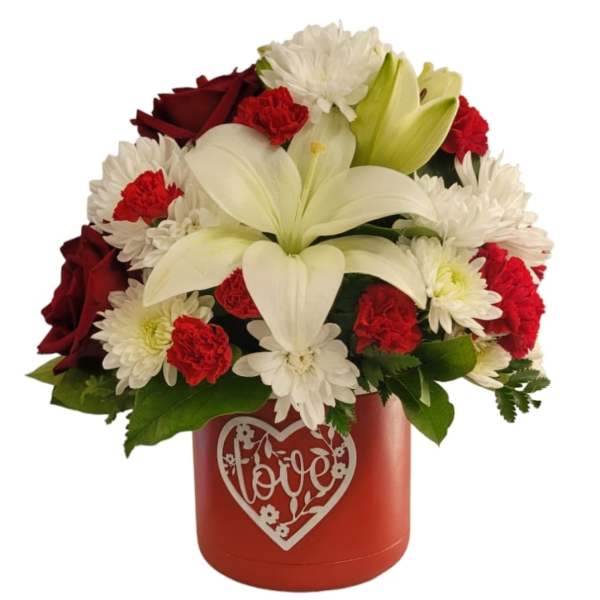 Red and white flower arrangement in a red heart-decorated box