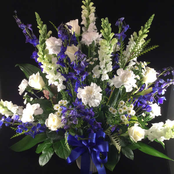 White and blue floral standing arrangement with a blue ribbon bow