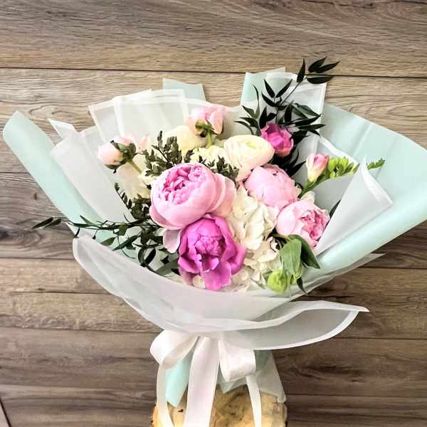 Bouquet of pink and white peonies wrapped in pastel paper