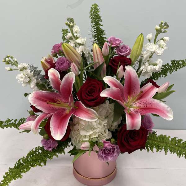 Pink lilies and red roses in a pink vase