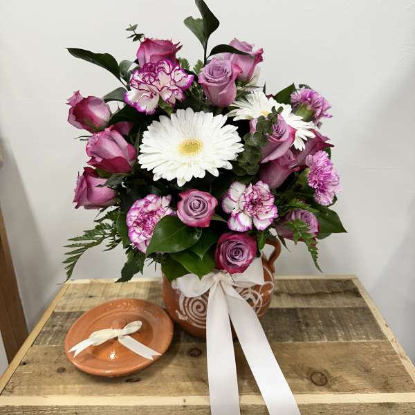 Pink and white flower arrangement in a terracotta vase with a white ribbon