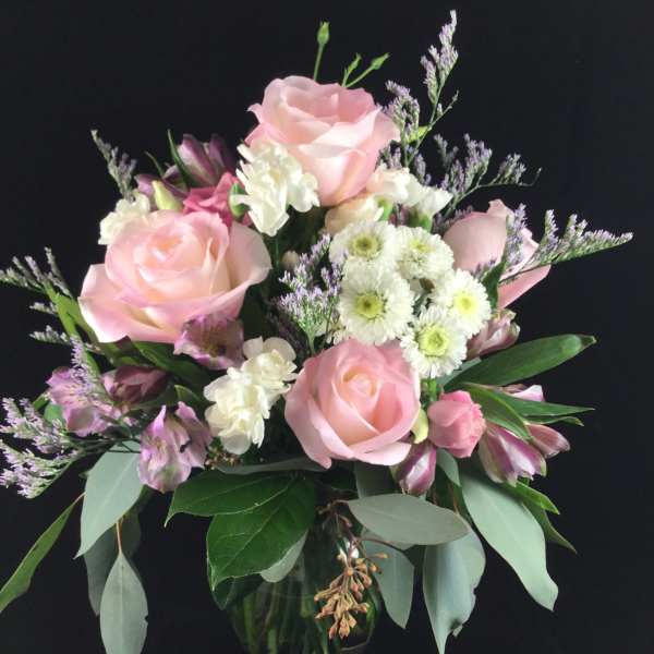 Pink roses and white flowers arranged in a glass vase
