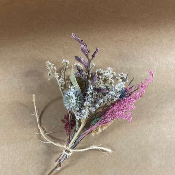 Small dried wildflower bouquet tied with twine on brown paper