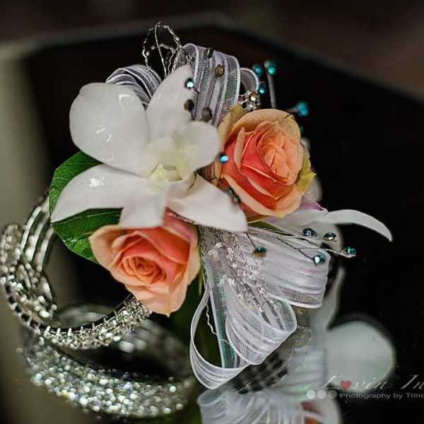 Small floral wrist corsage with peach roses and a white orchid on silver ribbon