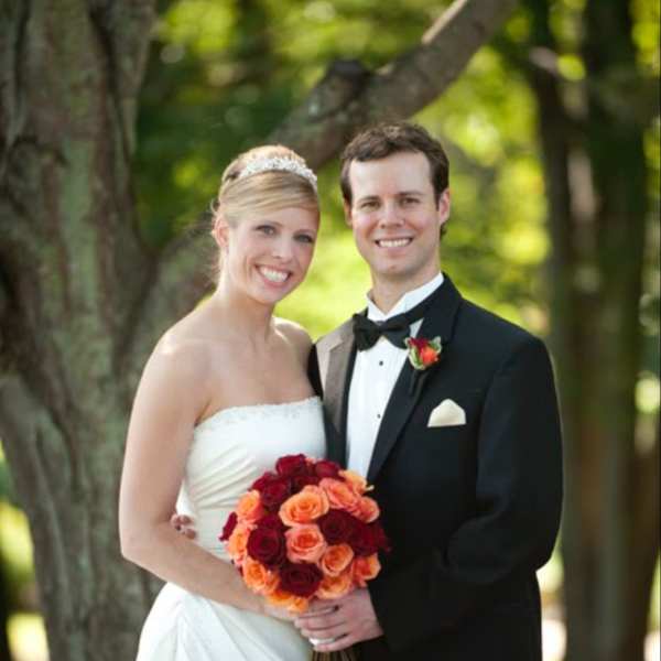 Bride and groom holding a bouquet of red and orange roses