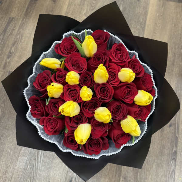 Bouquet of red roses and yellow tulips wrapped in black paper