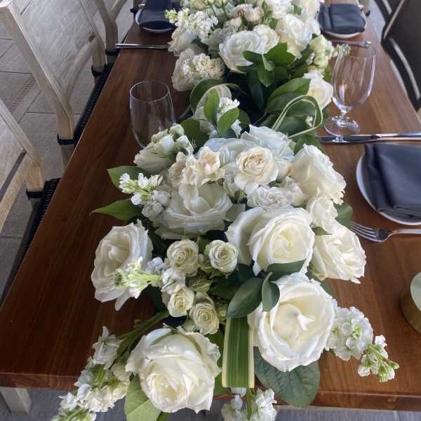 Long table centerpiece with white roses and greenery