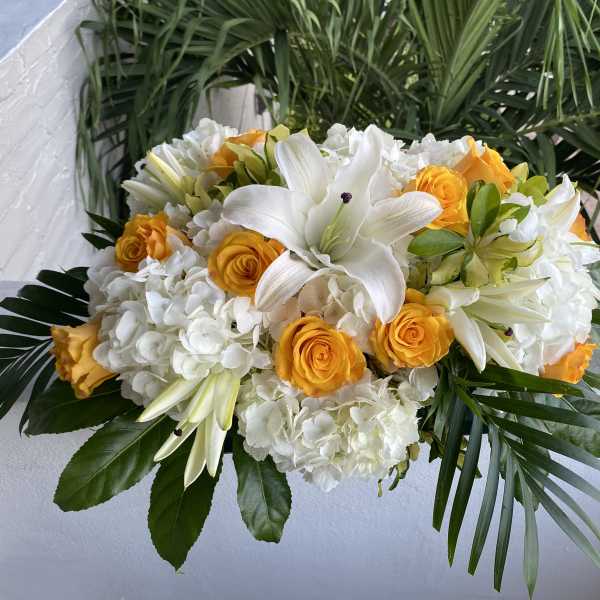 White lilies and yellow roses in a low floral arrangement