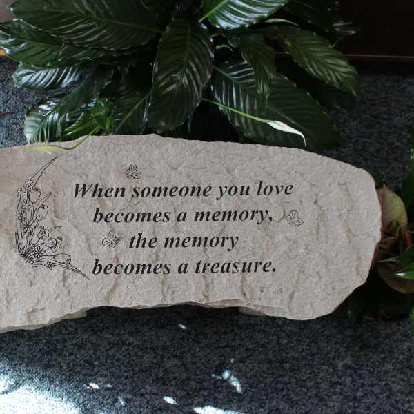 Memorial stone with an engraved sympathy quote surrounded by plants