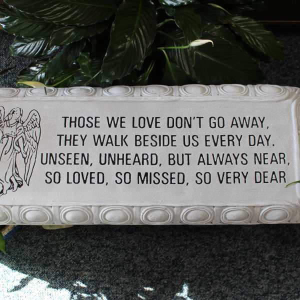 Memorial plaque with an angel and sympathy verse surrounded by plants