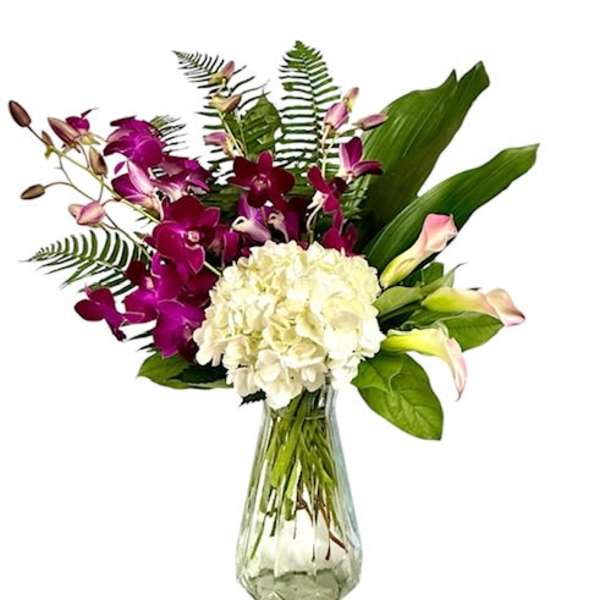 Purple orchids and white hydrangea in a clear glass vase