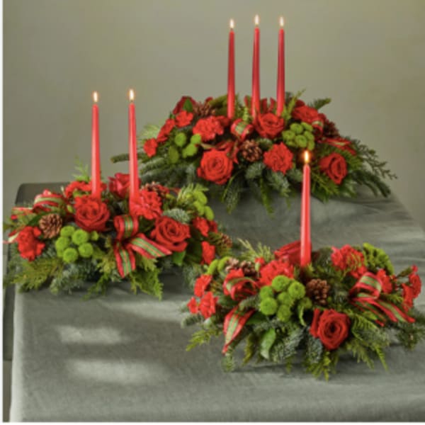 Three red floral candle centerpieces with tall taper candles
