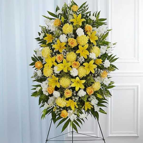 Standing floral spray with yellow lilies, roses, and white flowers