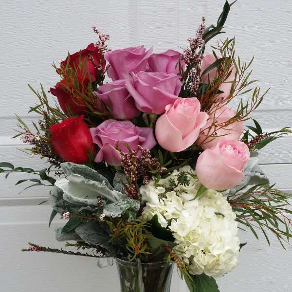 Bouquet of pink, red, and white roses in a clear glass vase
