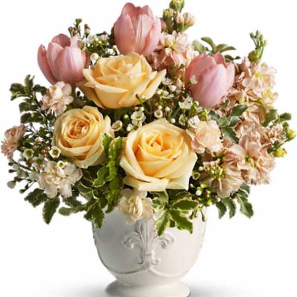 Pink tulips and pale yellow roses in a white vase