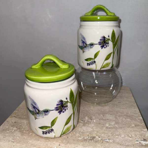 Two ceramic jars with green lids and hummingbird floral designs