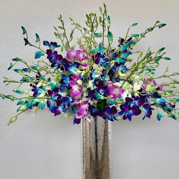 Colorful orchid arrangement in a tall metallic vase
