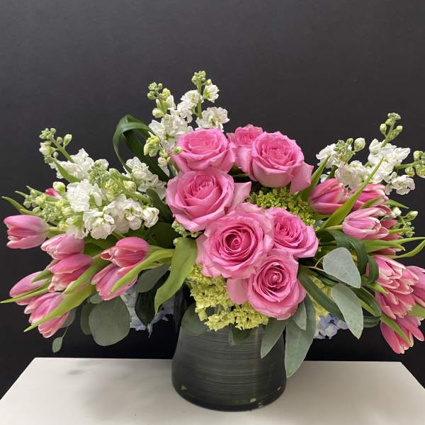 Pink roses and tulips arranged in a black vase