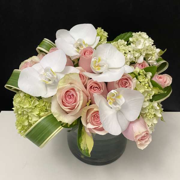 Pink roses and white orchids in a dark vase