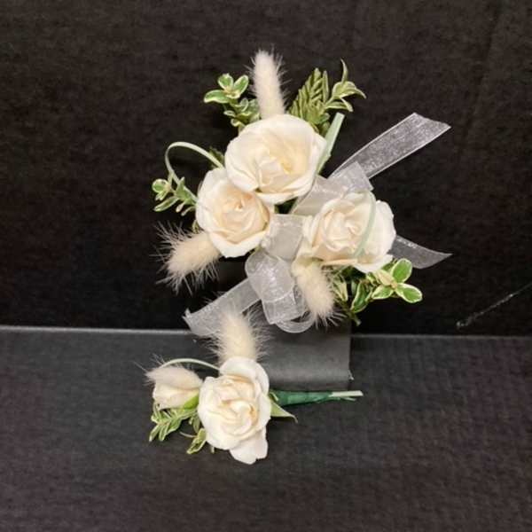 White rose corsage and boutonniere with ribbon on a dark background