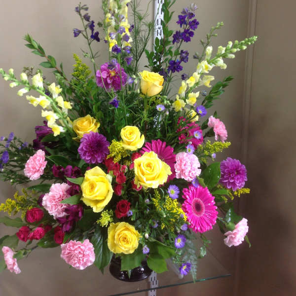 Tall mixed bouquet with yellow roses, pink gerberas, and purple flowers in a vase