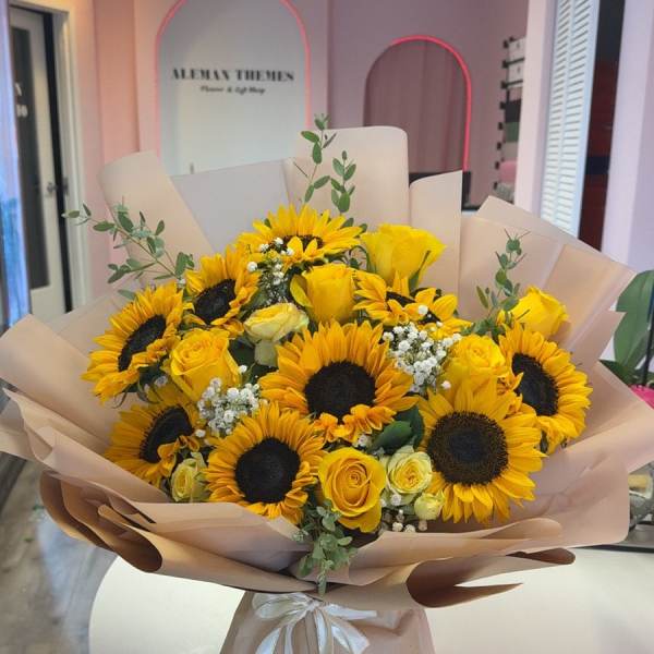 Bouquet of yellow sunflowers and roses wrapped in blush paper