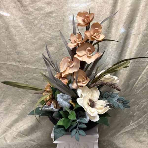 Tall floral arrangement with orchids and a white bloom in a pedestal vase