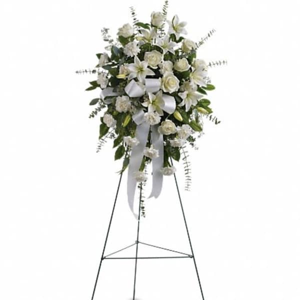 White floral standing spray on an easel with ribbon streamers