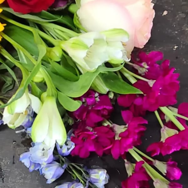 Mixed bouquet with roses, tulips, and purple blooms on a dark surface