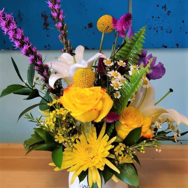 Colorful mixed bouquet in a white vase with yellow, white, and purple blooms