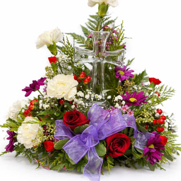Floral arrangement with a clear glass cross and purple ribbon