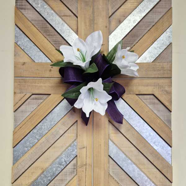 White flowers with a purple ribbon on a geometric wood wall hanging