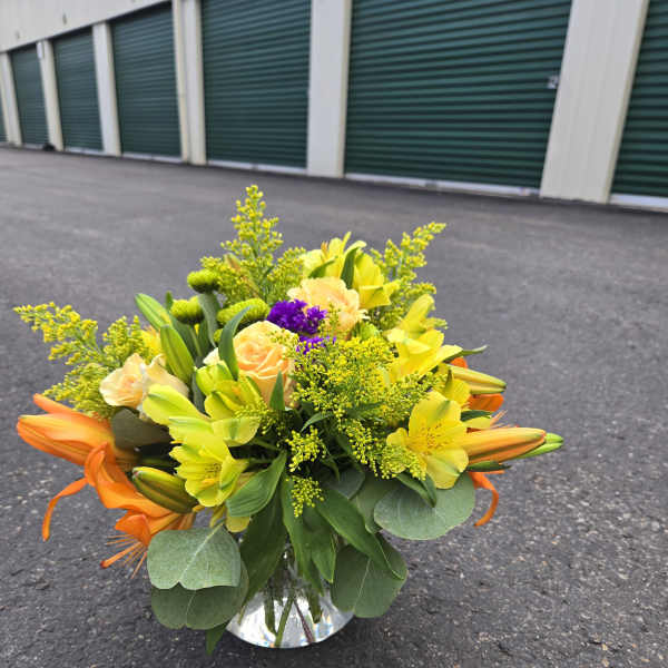 Yellow and orange mixed flower arrangement in a clear vase