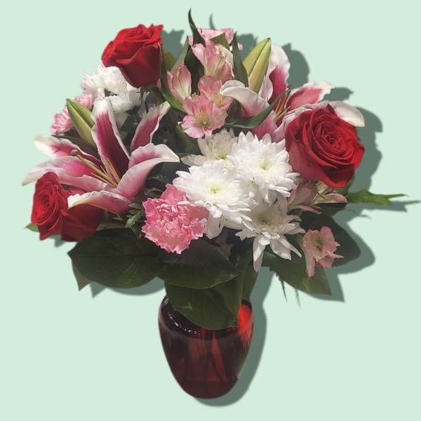 Bouquet of red roses, pink lilies, and white daisies in a red vase