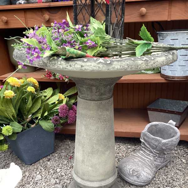 Purple flowers arranged in a stone birdbath planter