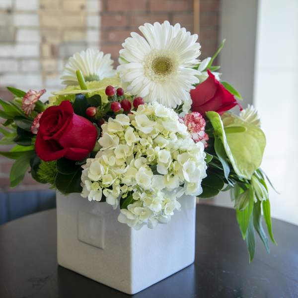 Red roses and white daisies in a white square vase