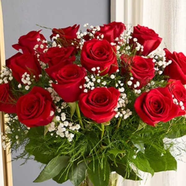 Red roses arranged in a clear glass vase with baby's breath