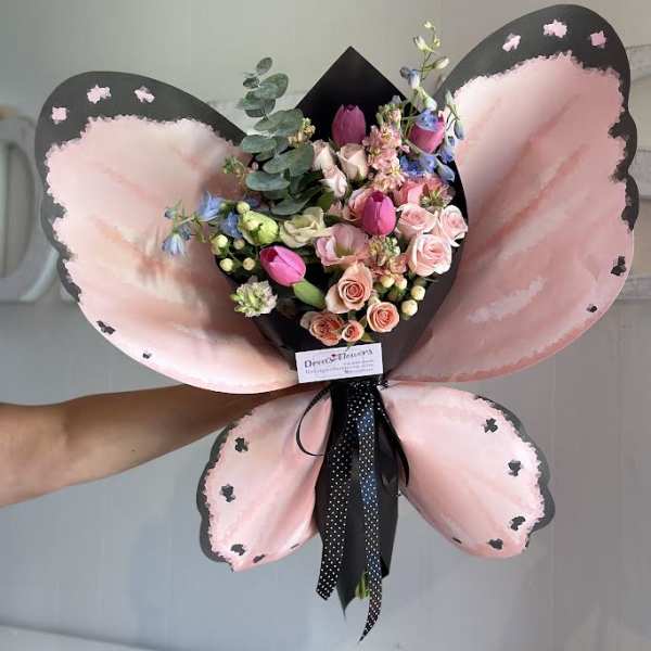Pink and black butterfly-shaped bouquet with mixed flowers and ribbon