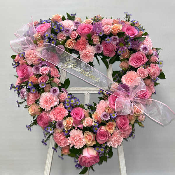Heart-shaped floral wreath with pink roses, carnations, and purple daisies