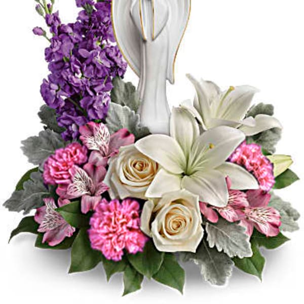 White angel figurine surrounded by purple and pink flowers