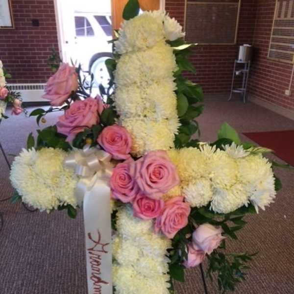 Floral cross arrangement with pink roses and white flowers