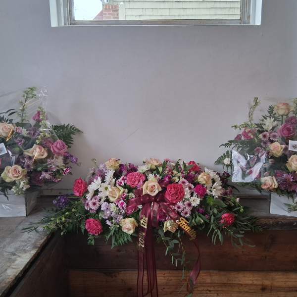 Floral sympathy arrangement with pink and cream roses and daisies