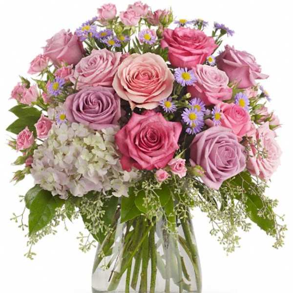 Pink and lavender roses with small purple daisies in a glass vase