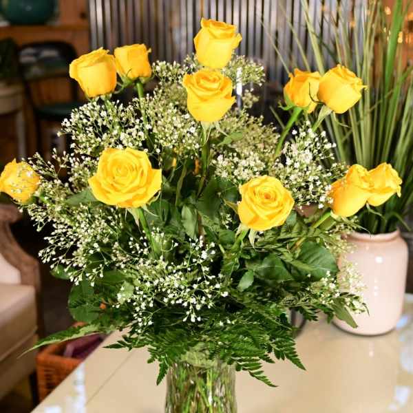 Yellow roses arranged in a clear glass vase with baby's breath