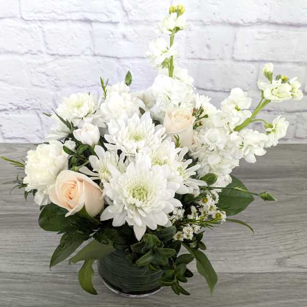 White floral arrangement in a glass vase with roses and chrysanthemums